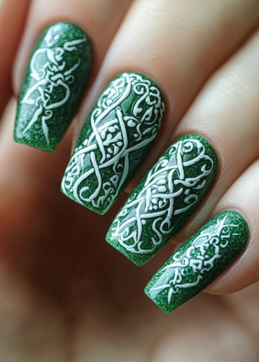 Elegant green nail art with intricate white Celtic designs and shimmering finish.