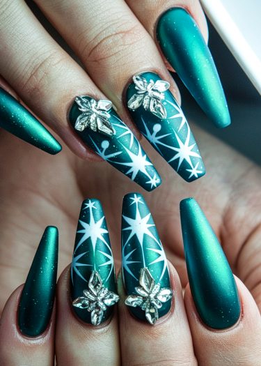 Exquisite metallic teal stiletto nails with intricate white patterns and silver floral embellishments.