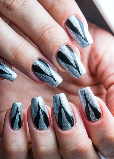 Elegant silver glitter nail art with bold black abstract patterns for a striking look.