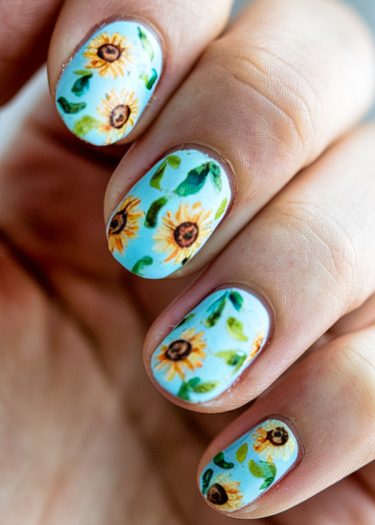 Elegant blue sunflower nail art with vibrant floral designs and detailed greenery accents.