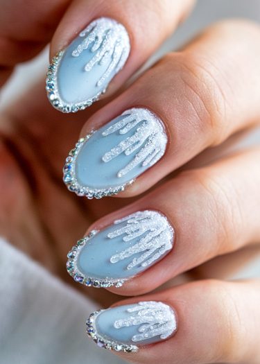 Elegant soft blue winter nail art with silver glitter and rhinestones for a frosty look.