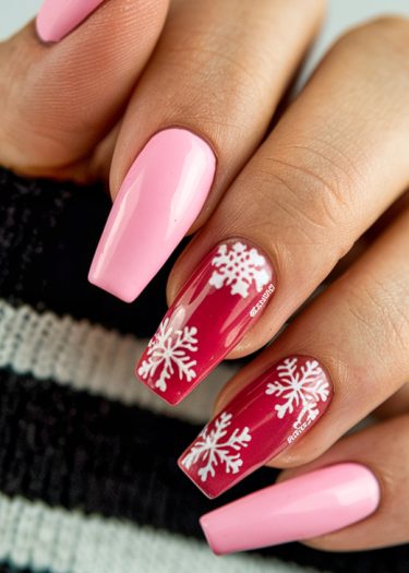 Elegant pink and red nail art with winter snowflakes on a stylish hand.