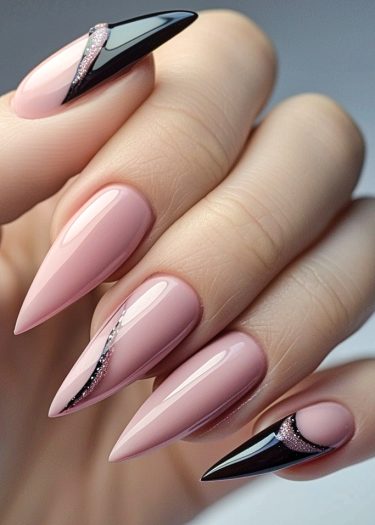 Elegant almond-shaped nails featuring soft pink polish with striking black tips and silver accents.