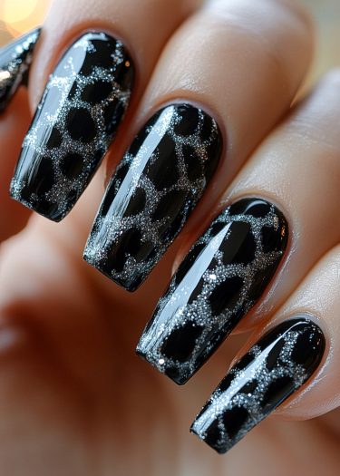 Elegant black nail art with silver glitter animal print design for a chic look.