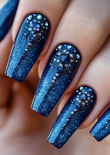 Elegant deep blue glitter nails adorned with sparkling rhinestones for a glamorous look.