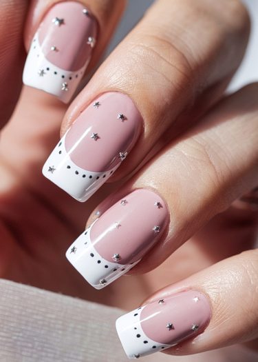 Elegant pink French manicure with metallic stars and black dots for a chic nail design.