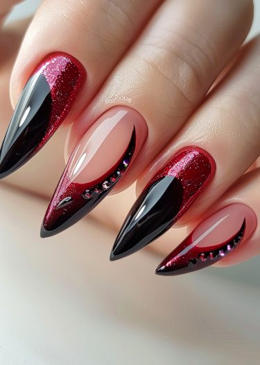 Elegant stiletto nails with glossy black and glittery red design and rhinestone accents.