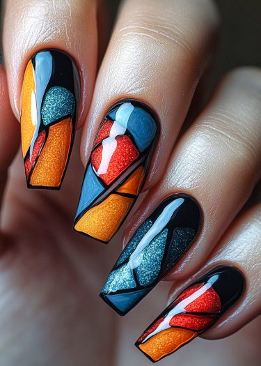 Vibrant stained-glass nail art featuring geometric patterns in orange, red, and blue hues.