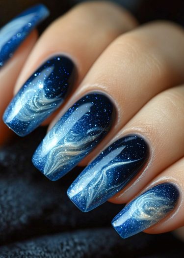 Stunning starry night nail art featuring deep blue base, swirling clouds, and twinkling stars.