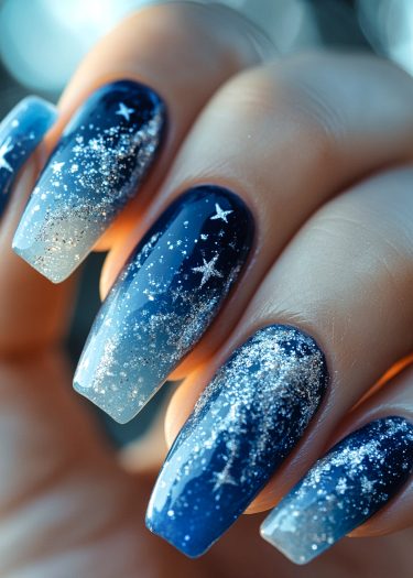 Elegant starry night nail art featuring ombre blue shades and glittering cosmic accents.