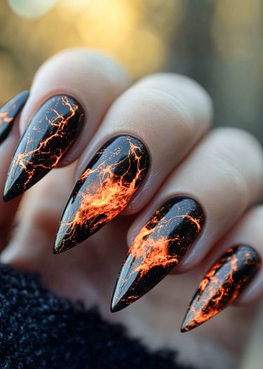 Stiletto black nails with fiery lava patterns in orange and red create a dramatic effect.