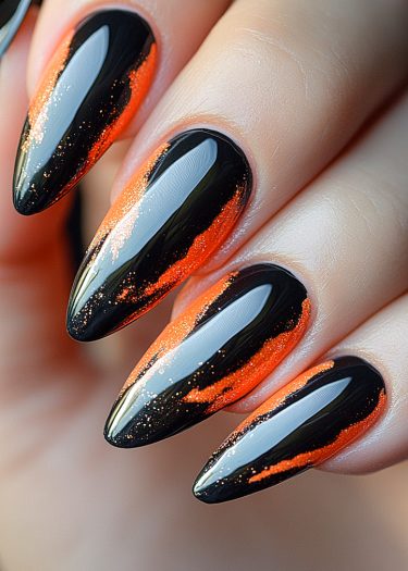 Bold stiletto nails with glossy black base and vibrant orange flame design for a striking look.