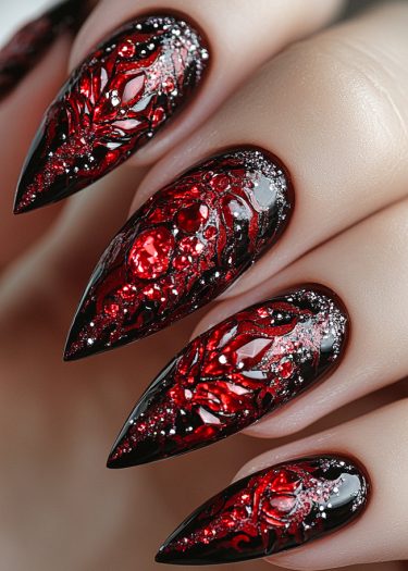 Stunning stiletto red and black nail art with jeweled accents and glitter highlights.