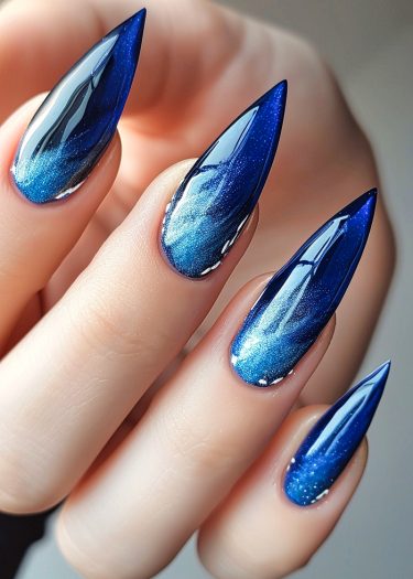 Elegant stiletto nails featuring a stunning blue gradient and glossy finish.