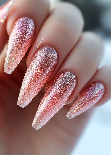 Elegant almond-shaped stiletto nails with sparkling pink gradient and glitter shine.