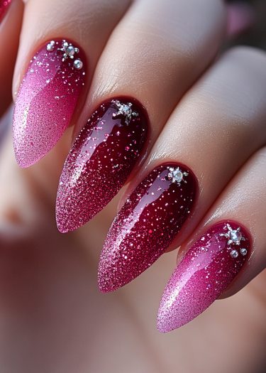 Stunning stiletto nails with gradient red to pink, glitter accents, and crystal embellishments.