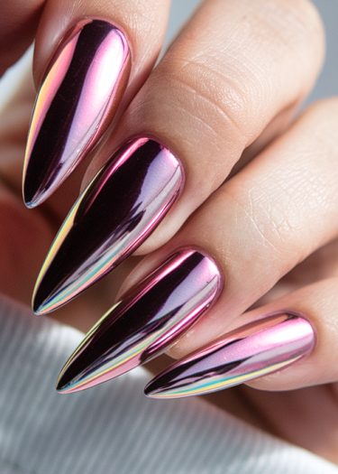 Stunning stiletto nails with chrome finish in pink and purple hues on a smooth hand.