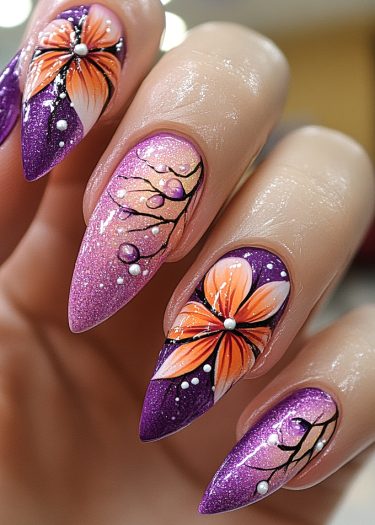 Vibrant stiletto nail art featuring floral designs and glitter in purple and pink hues.