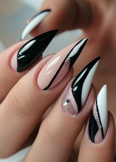 Elegant stiletto nail art design featuring black, white, and nude-pink with glitter accents.