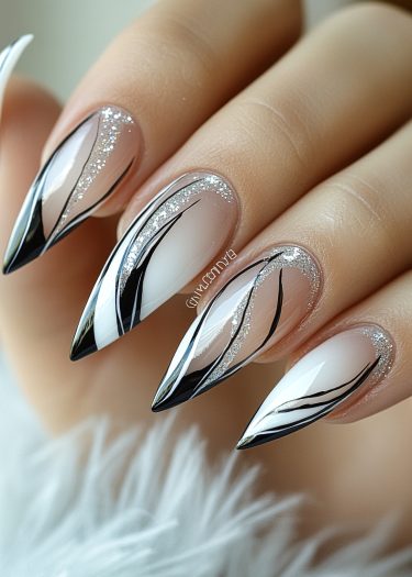 Stiletto nails featuring elegant black and silver designs with an ombre nude to white gradient.