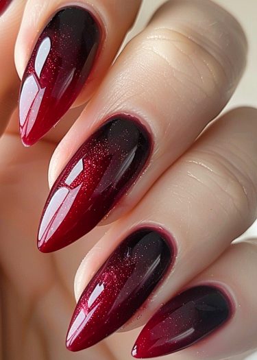 Stylish stiletto ombre nails in vibrant red with shimmer, showcasing sleek, modern nail art.