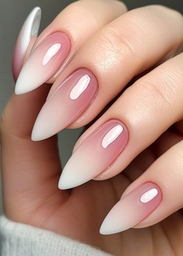 Elegant almond-shaped stiletto nails with ombre design in pink to white, showcasing luxurious nail art.