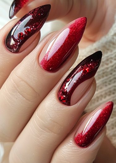 Glamorous stiletto nails featuring red ombre design and sparkling rhinestones for an elegant look.