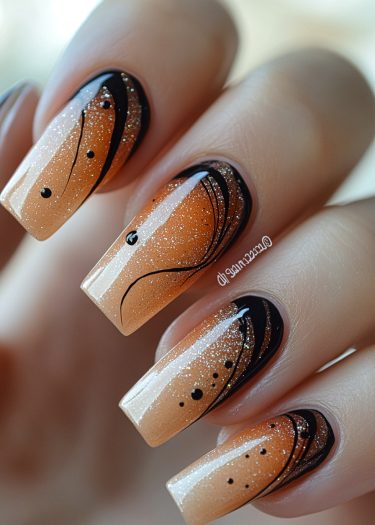 Elegant coffin nails featuring a warm gradient, black art, and shimmering glitter accents.