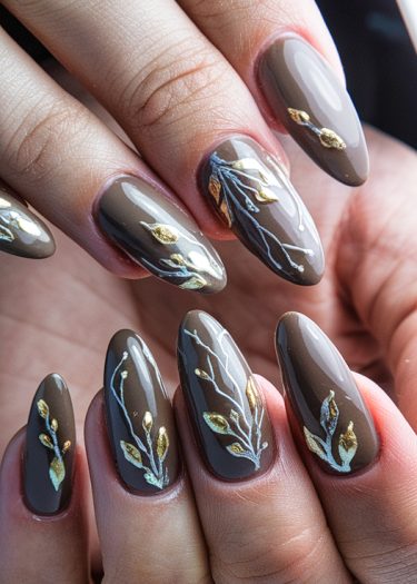 Elegant taupe botanical nail art with golden accents and intricate white designs.