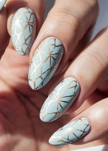 Elegant almond-shaped teal nails adorned with intricate gold geometric designs.