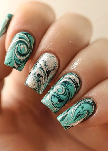 Elegant teal, black, and silver marbled nail art with glitter for a stunning manicure.