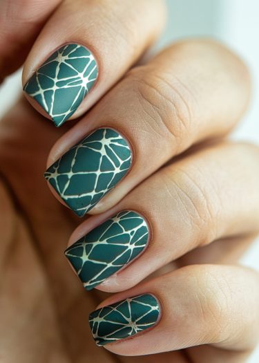 Elegant teal geometric nail art with intricate white patterns on manicured nails.