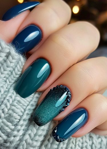 Elegant deep teal and navy blue manicure with ombre and glitter accents on long oval nails.