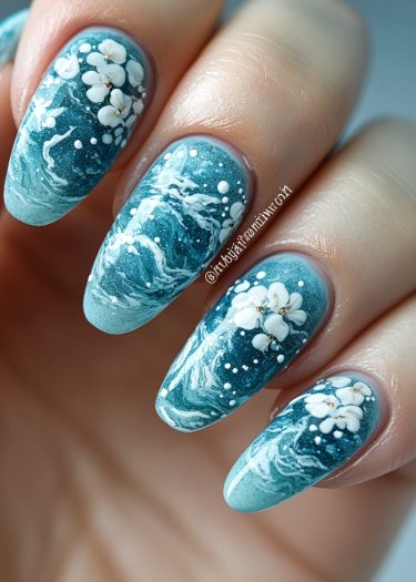 Elegant teal marble nail art featuring floral designs and ocean wave patterns.