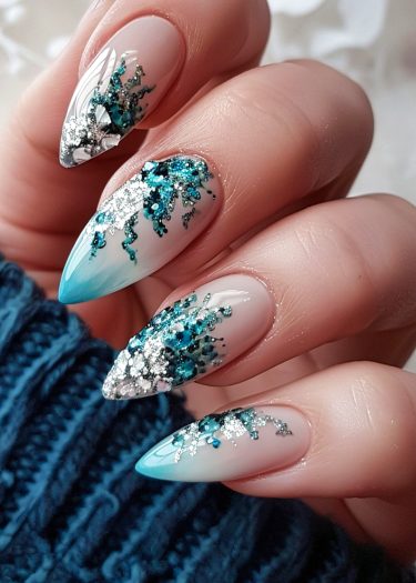 Elegant teal and silver stiletto nails with intricate gradient and decorative embellishments.