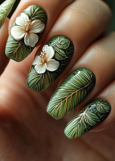 Tropical leaf nail art featuring green foliage, hibiscus flowers, and elegant gold accents.