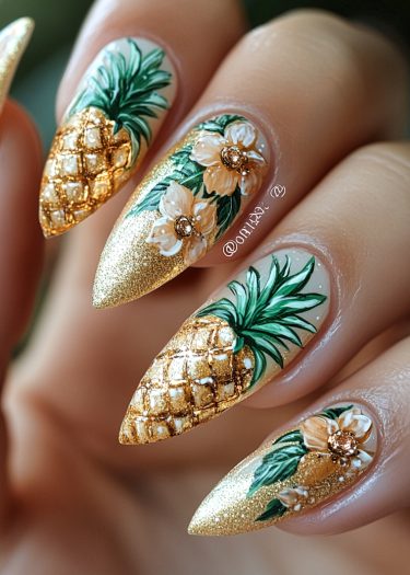 Stunning tropical nail art featuring gold, pineapples, and floral designs on almond-shaped nails.