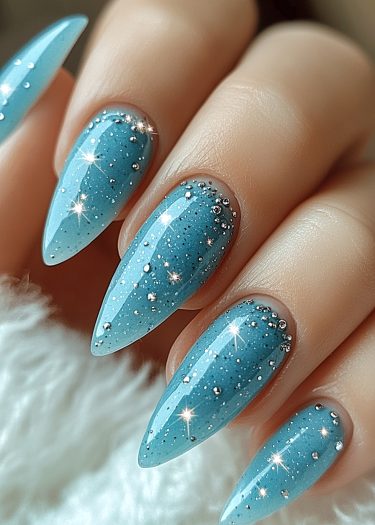 Elegant stiletto nails adorned with turquoise polish and silver beads on a soft background.