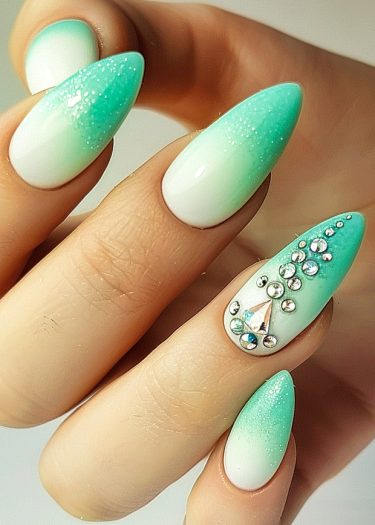 Elegant stiletto nails with turquoise gradient and rhinestone accents for a sophisticated manicure.