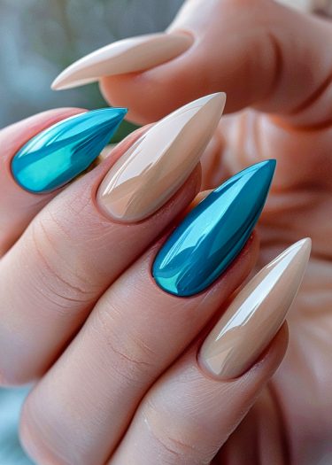 Stylish stiletto nails featuring turquoise and nude polish in a modern design.