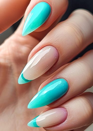 Stunning turquoise stiletto nails with glittery nude accents and modern French tips.