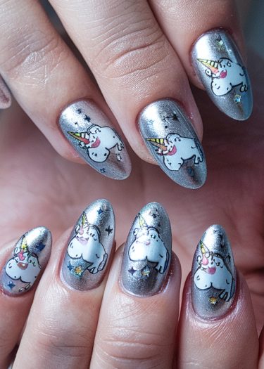 Whimsical unicorn nail art design on metallic silver nails, blending elegance with playful charm.