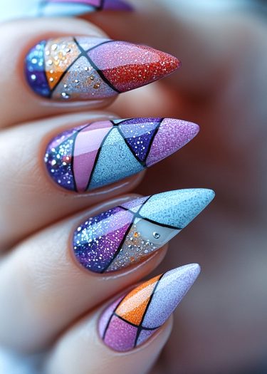 Stunning stiletto nails featuring vibrant geometric patterns and elegant glitter accents.