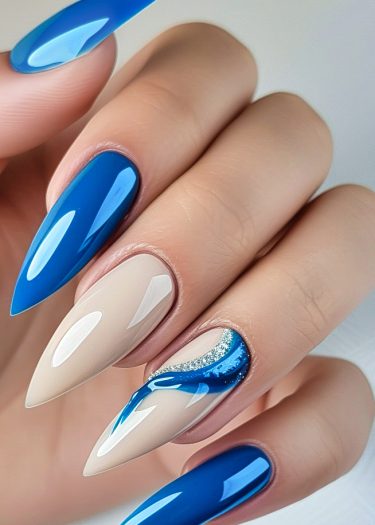 Elegant almond-shaped nails in royal blue and nude beige with intricate designs and sparkle.