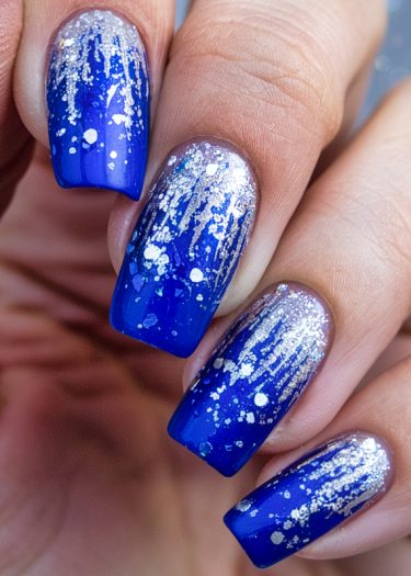 Vibrant blue glitter nails with a cascading silver sparkle, perfect for glamorous occasions.