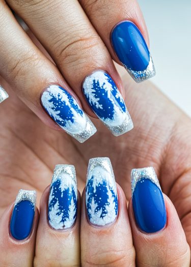 Stunning winter-themed blue nail art with glitter tips and intricate snowflakes for festive elegance.