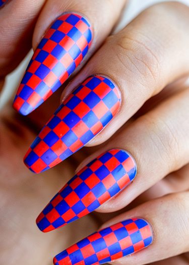 Vibrant red and blue checkerboard nail art on elegantly shaped almond nails.