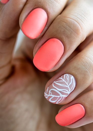 Elegant coral matte nails with intricate white leaf design on ring finger.