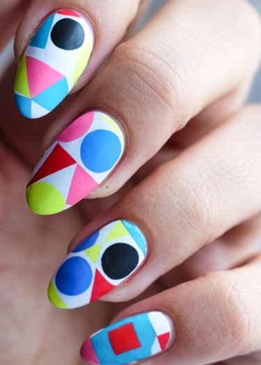 Colorful geometric nail art featuring vibrant patterns and bold shapes in various hues.