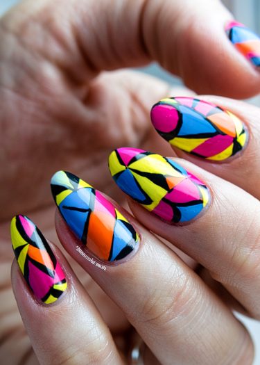 Vibrant stained glass geometric nail art featuring bold colors and intricate designs.